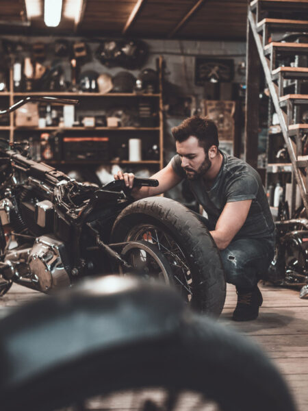 Man repairing bike. Man repairing bike. Confident young man repairing motorcycle in repair shop
