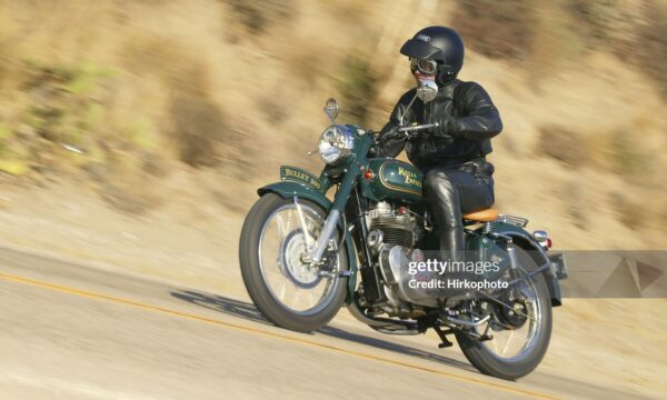 Ojai, California USA - August 24, 2005 : Retro looking motorcycle and rider pan shot, Royal Enfield bullet 500 is a throw back to the 1940's. This currently manufactured motorcycle is unchanged timeless design.
