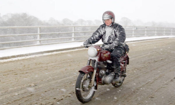 A motorcyclist on a vintage Royal Enfield motorbike during a snowstorm, November 2005. He is crossing a bridge over the A30 in Cornwall, when Bodmin Moor was blocked. (Photo by Glyn Howells/Getty Images)